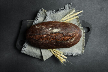 Fragrant black oval bread. On a black stone background. Top view.