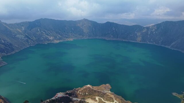 Quilotoa crater lake glimmering with turquoise waters nestled among volcanic mountains under cloudy skies in Ecuador