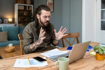 Finance and economy. Young man, small business owner, working online at home office, preparing for video call for presentation and online coaching. E-commerce professional occupation freelance work