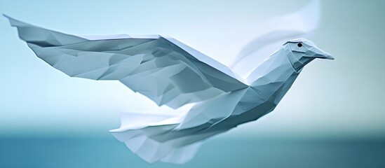 Obraz premium White origami seagull bird in flight with soft blue gradient background and subtle waves creating a serene coastal atmosphere.