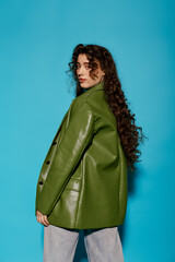 Naklejka premium Stylish woman with curly hair poses confidently against vibrant blue backdrop in urban setting