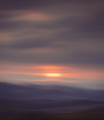 Soft blurred background of a natural landscape at dusk with gentle hues of orange and purple