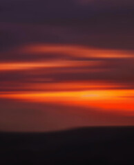 Abstract blurred sunset over distant hills in soft focus, creating a serene and tranquil setting