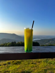 Cocktail with a straw in a glass against the backdrop of autumn mountains