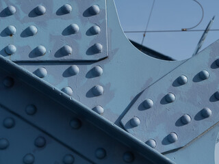 Close-up of a riveted steel structure painted blue, part of a bridge. Industrial detail, abstract texture, civil engineering concept
