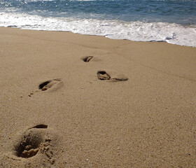 Fine golden sand covering a beach during a sunny day with clear skies, creating a serene and tranquil atmosphere for relaxation