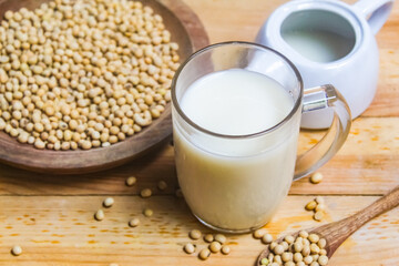 a glass of soy milk with soy beans on the table