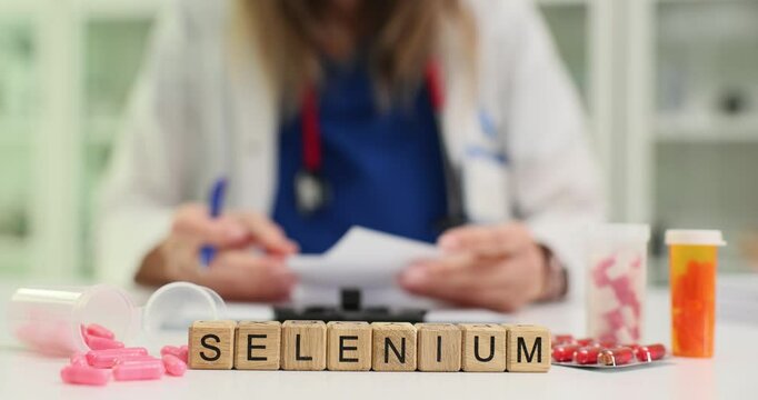 Word Selenium and scattered pills against working doctor in hospital. Doctor writes prescription for supplements to support patient health at appointment
