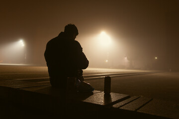 Solitude in the Fog, A man sits on a bench in the fog and looks at his smartphone, in the...