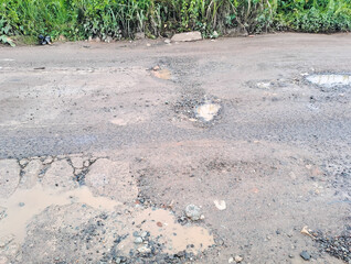 broken asphalt road. the asphalt road with potholes and waterlogged after the rain	
