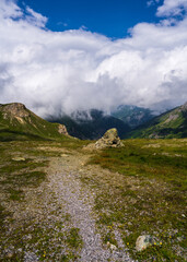 Large white clouds float across blue sky above mountain peaks along Grossglocknerstrasse, Austrias famous high mountain road. Place for nature tourism, traveling in alps