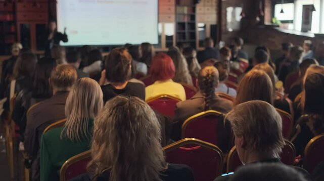 Large group of people attending educational event in comfortable indoor venue with speaker.
