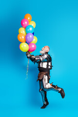 Knight in armor with colorful balloons, standing on a bright blue background, symbolizing contrast