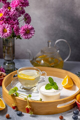 Relaxing tea time with yogurt and fresh fruits on wooden tray