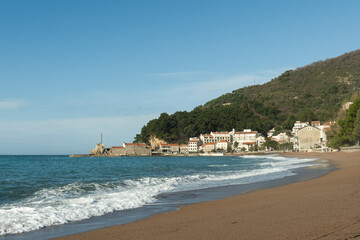 Mediterranean coastal town and beach with a mountain backdrop.