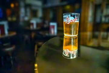A glass of beer on the table. Bar in the blurred background with no people. 09/03/2024