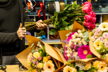 Florist arranging pink roses and colorful flowers for bouquet creation
