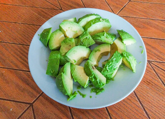 Fresh avocado slices on a light blue plate, a vibrant and healthy food image perfect for recipes, blogs, or healthrelated content.  The rustic wooden background adds a touch of natural warmth.