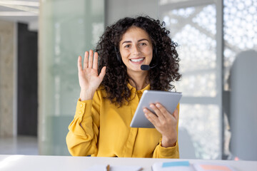 Professional Woman Using Tablet and Speaking on a Headset in an Office.