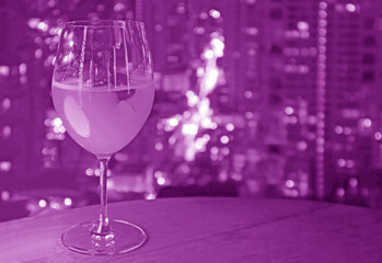 Pop art style purple colored glass of cocktail with blurry skyscrapers night view in the backdrop