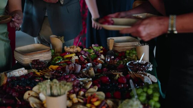 An inviting charcuterie spread during the cocktail hour at a fall wedding. Guests reach for food from a colorful table filled with fruits, cheeses, and snacks at a rustic winery venue in South Georgia