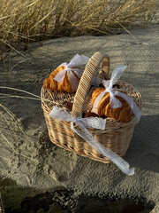 A wicker picnic basket with croissants tied with lace.