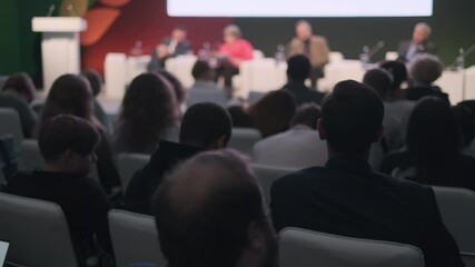 People listening to panel speakers at a conference in a formal setting, engaging and learning.