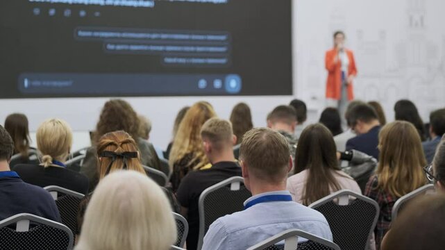 Conference audience attentively listening to a presenter giving a talk in professional setting