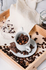 coffee beans in a white cup on a wooden background, light still life, chocolate, espresso, Americano
