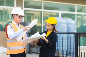 Asian male and female engineers inspecting outdoor work in hard hats and real estate agents or managers discussing blueprint plans with digital tablets.