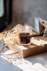 coffee in a glass cup in the morning sunlight on the windowsill, gypsophila flowers, white flowers, open book, morning coffee