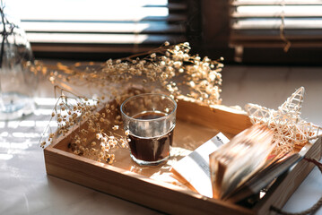 coffee in a glass cup in the morning sunlight on the windowsill, gypsophila flowers, white flowers, open book, morning coffee