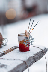 sparklers in a vase on a wooden bench in a winter yard, Christmas, New Year, winter holidays, snow on a bench in the park