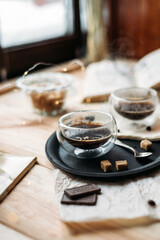 Coffee in glass cup on wooden background, espresso coffee in double-bottomed glass cups, cane sugar, open book, coffee on a black tray, lunch break, coffee still life close-up