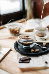 Coffee in glass cup on wooden background, espresso coffee in double-bottomed glass cups, cane sugar, open book, coffee on a black tray, lunch break, coffee still life close-up