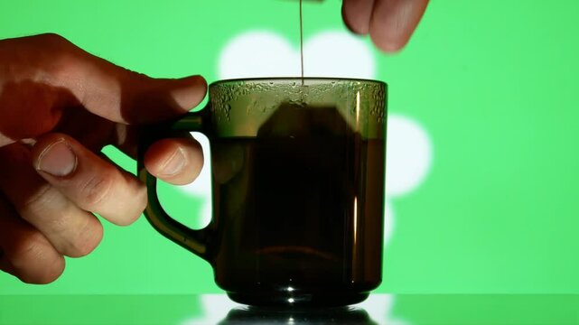 Two male hands taking a glass cup of tea with a hanging tea tag of Saint Patrick's Day date close-up