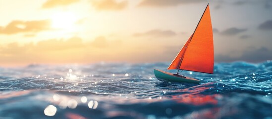 Small sailboat gliding across ocean waves at sunset with vibrant orange sail and blurred background for text placement