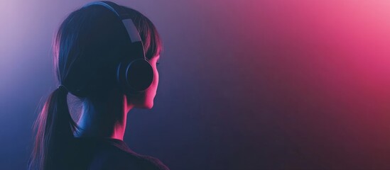 Naklejka premium Young woman enjoying music with headphones in vibrant lighting creating a serene atmosphere and space for custom text or branding.