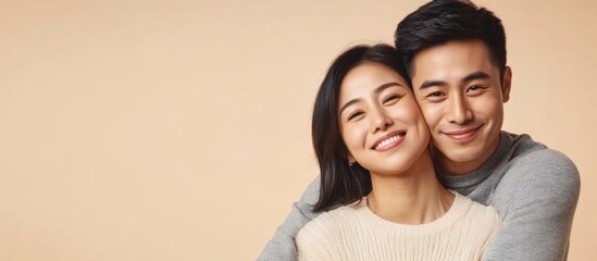 Happy young Asian couple sharing a warm embrace with an empty background for personalized text or messaging.