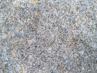 A close-up shot of a rough, textured rock surface, showcasing its granular composition and varying...