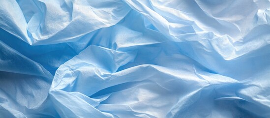 Obraz premium Light blue crumpled tissue paper texture with soft patterns and folds ideal for backgrounds and creative design projects.