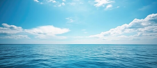 Serene blue sky with scattered clouds above tranquil ocean waters creating a peaceful natural landscape scene.