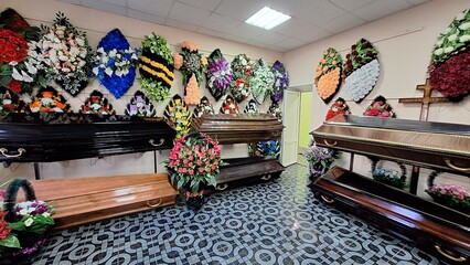 Funeral home interior with coffins and floral arrangements display.