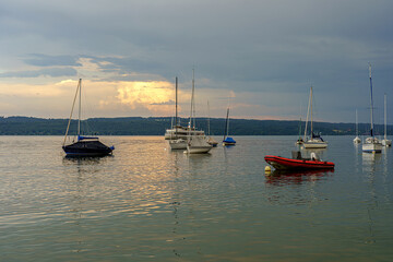 Sailboats and boats on the water against the backdrop of a gloomy evening sky.