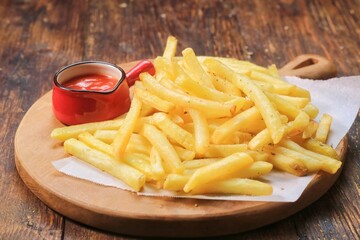 French fries with ketchup on wooden board 
