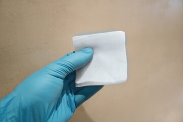 Hand holding a medical sterile gauze pad with a neutral background