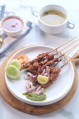sate ayam or chicken satay, famous traditional Indonesian food, chicken meat on bamboo sticks and grilled, served on a plate