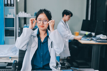 Positive doctor working on laptop in medical office, portrait.