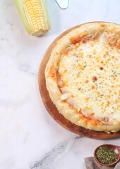 Homemade cheese tuna melt pizza with sweet corn on woodden tray. Selective focus
