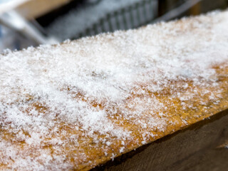 A light dusting resembling snow blankets a wooden surface, creating an interesting contrast in a serene winter environment